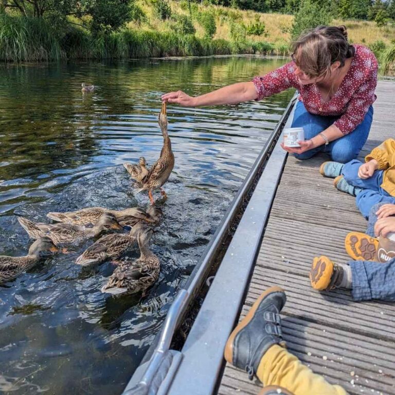 Tagesmutter Corinna beim Entenfüttern mit Kindern am Teich in Leipzig